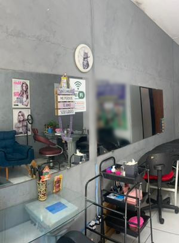 Estações de trabalho do salão com espelho grande na parede, bancada de vidro e carrinho auxiliar organizador
